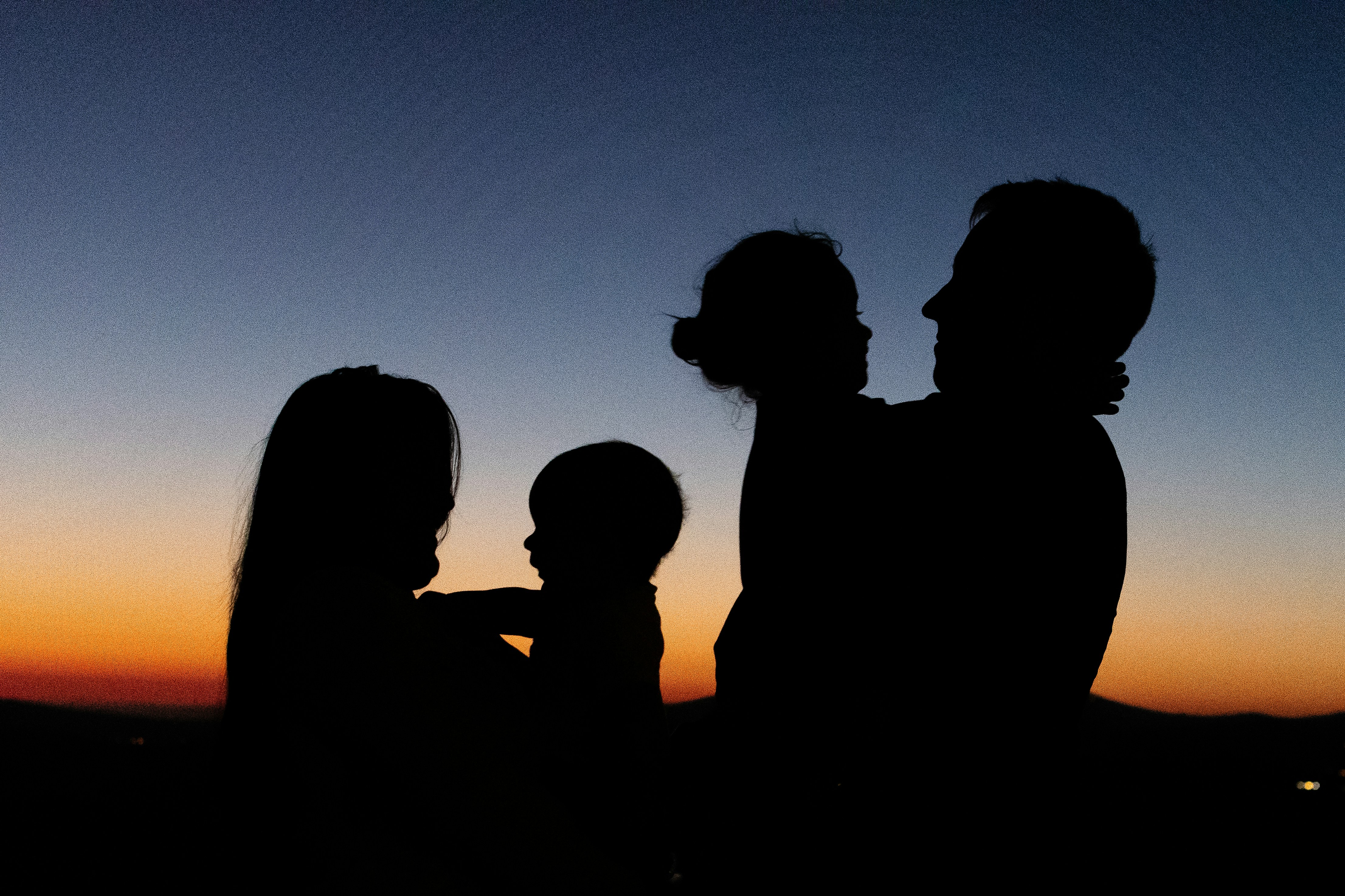 Une silhouette d'une famille tenant leurs enfants lors du coucher de soleil.